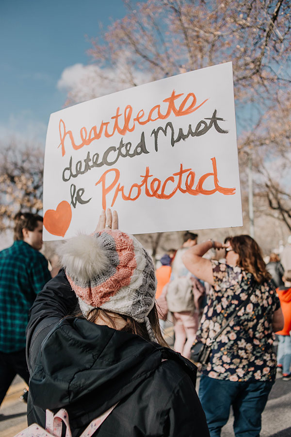 A marcher at the March for Life holding a hand-painted sign that reads "Heartbeats detected must be protected"